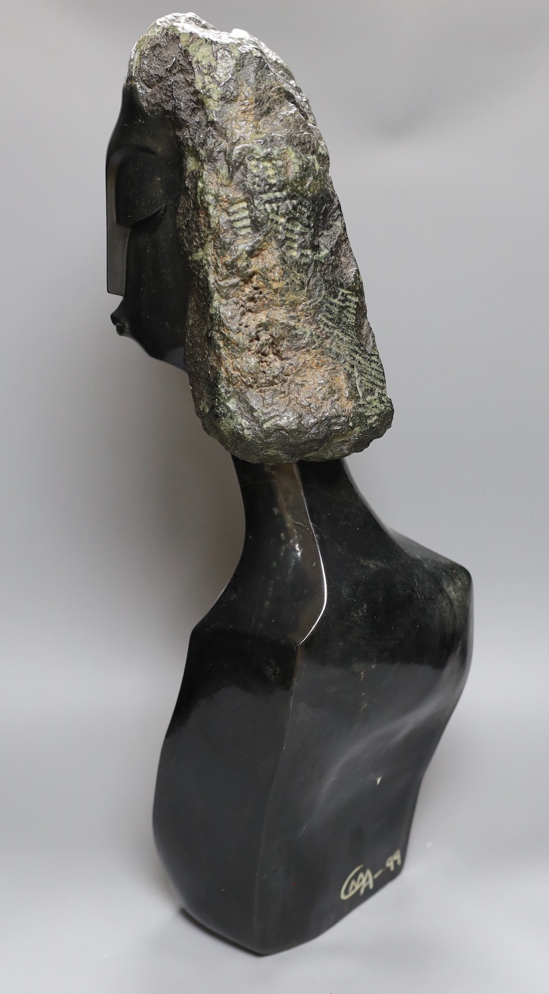 A Zimbabwean carved and polished stone head and upper torso of a woman, 61cms.